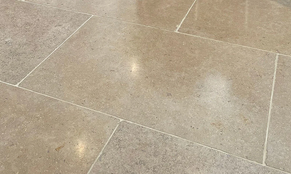 A close-up of polished beige limestone-effect kitchen floor tiles